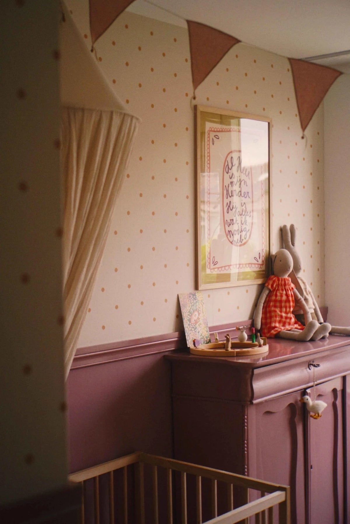 Kinderkamer wand met Atelier Chien Polkadot mini okergeel behang achter houten ledikant met hemeltje
