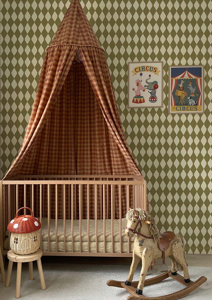 Kinderkamer wand met Atelier Chien Harlekijn olijfgroen behang achter ledikant met hemeltje