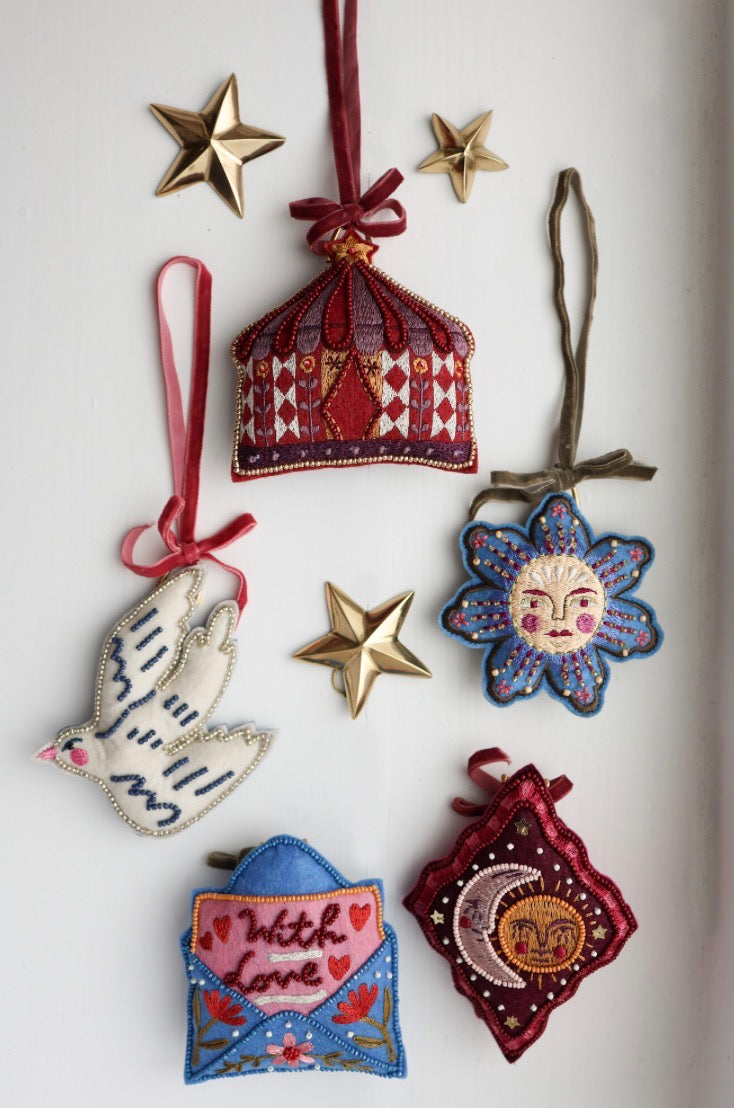 All The Luck In The World wit stoffen zwaluw ornament hangend naast een circus-, zon- en enveloppe-ornament