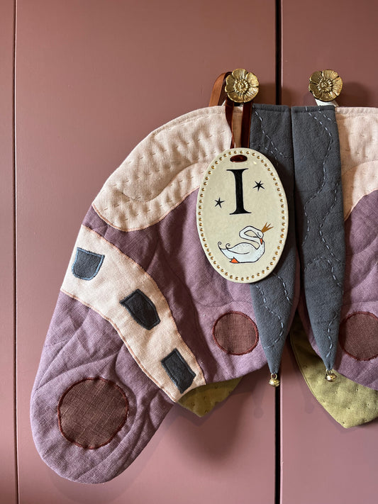 Handgemaakt letterbordje met letter I en zwaan bungelend aan een kledingkast in de kinderkamer