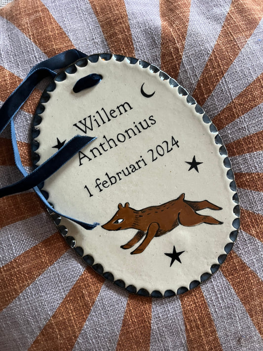 Detailopname van een handgemaakt geboortebordje met een rennend vosje en de naam Willem Anthonius