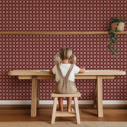 Sfeervolle kinderkamer wand met Atelier Chien Geblokt quilt bordeauxrood behang achter houten speeltafel