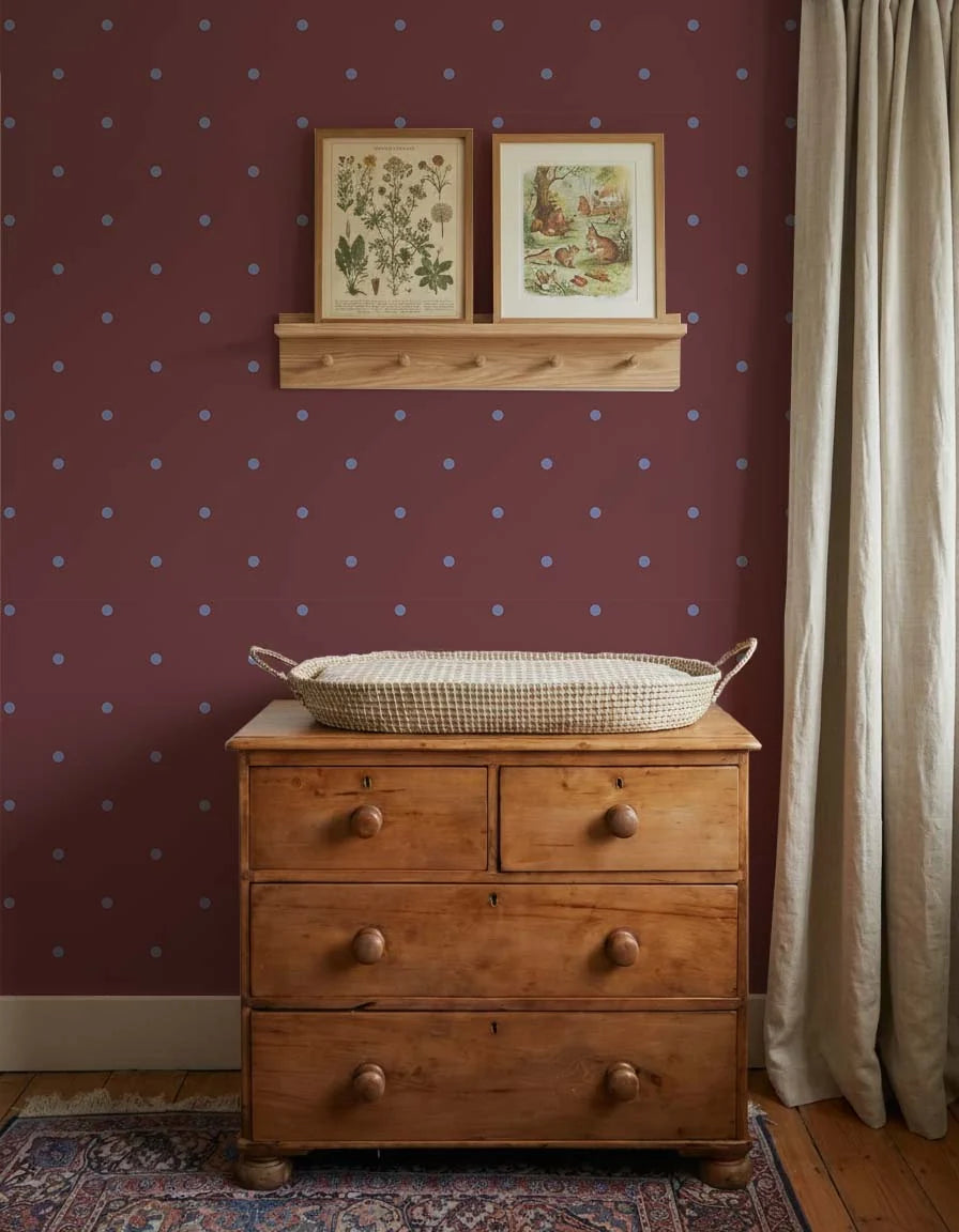 Babykamer wand met Atelier Chien Polkadot maxi bordeaux blauw behang achter houten commode met verschoonmandje