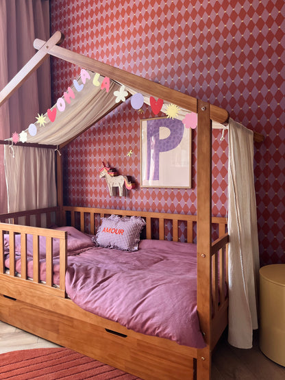 Huisjesbed in een kinderkamer met roze en rood harlekijn ruitenbehang van Atelier Chien.