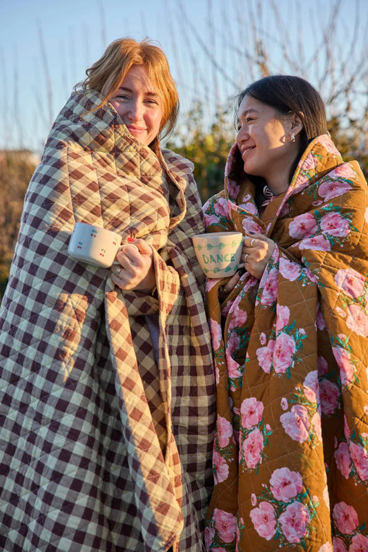 Twee vrouwen buiten gewikkeld in warme Rice gewatteerde katoenen plaids met ruitjes en bloemenprint