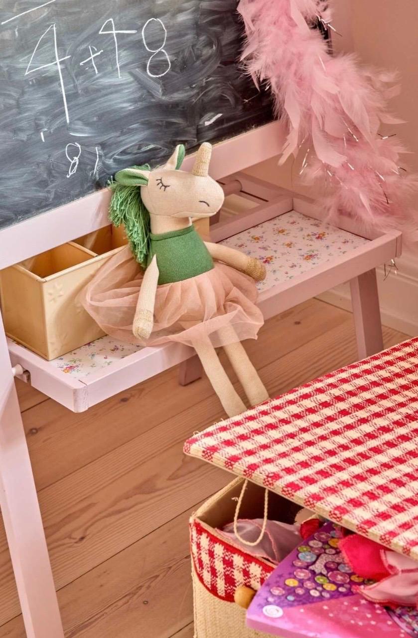 Rice gebreide eenhoorn knuffel met groene manen en roze tutu op kinderbureau